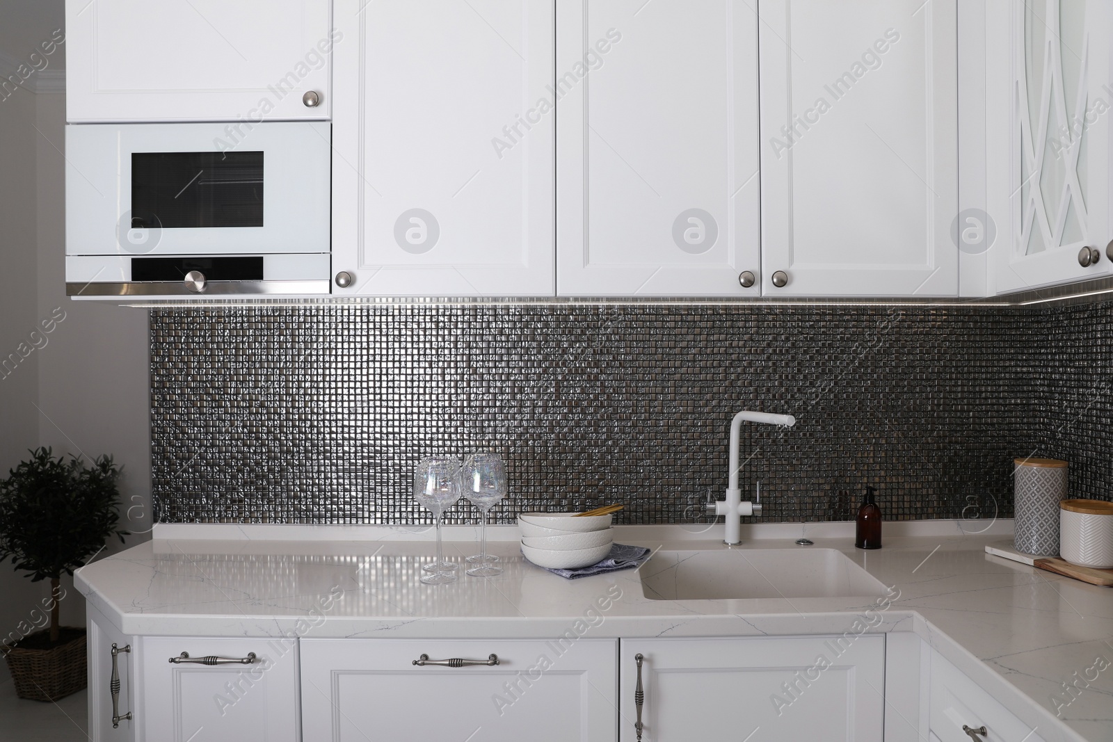 Photo of Beautiful ceramic dishware and glasses on countertop in modern kitchen