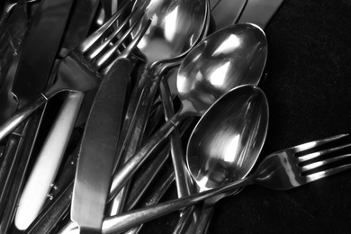 Photo of Silver spoons, forks and knives after washing on black table, flat lay
