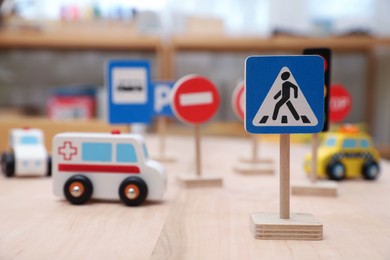 Photo of Different miniature road signs and cars on wooden table. Montessori toy