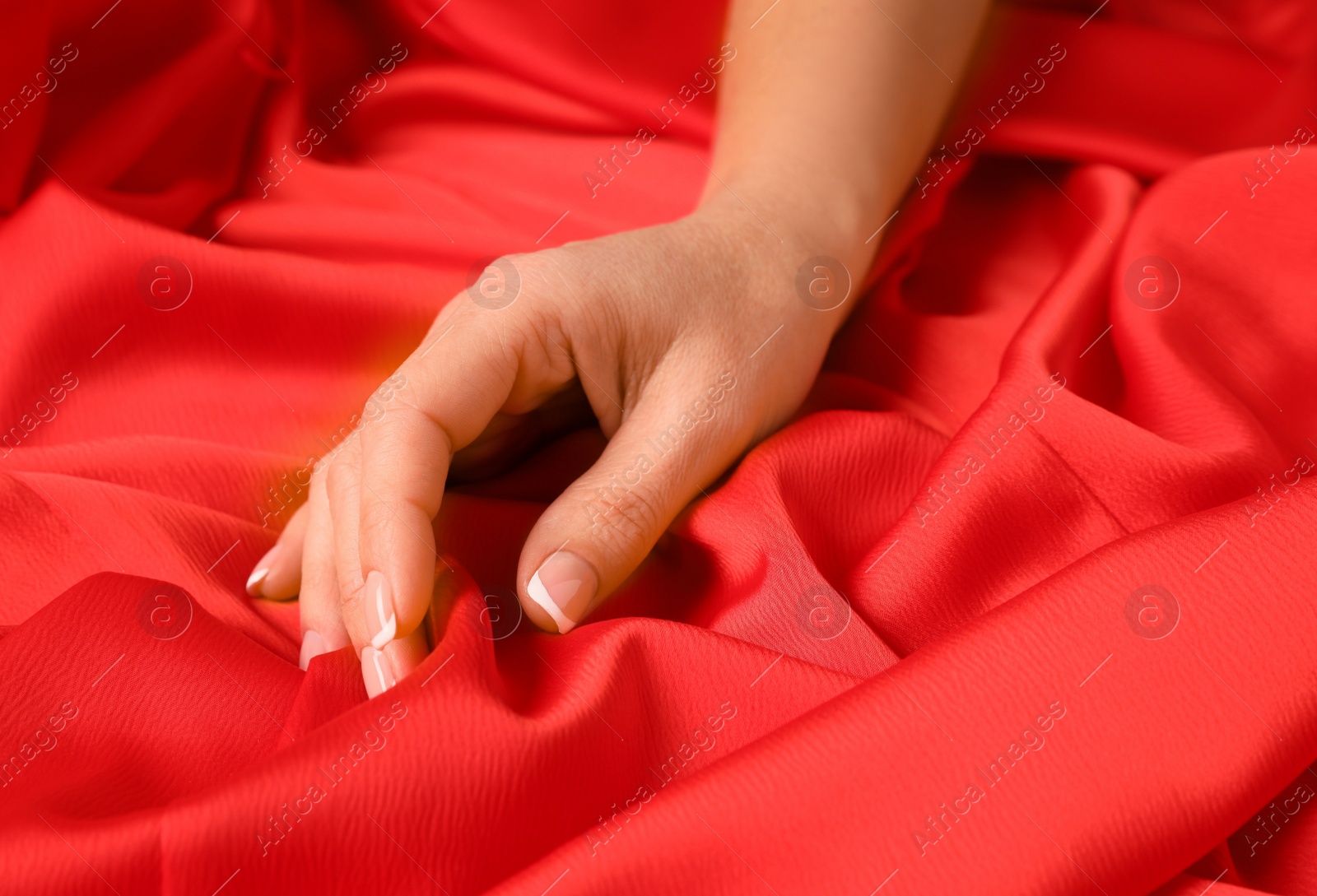 Photo of Woman touching smooth red fabric, closeup view