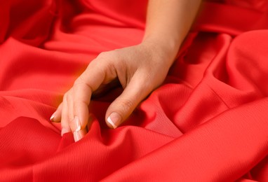 Photo of Woman touching smooth red fabric, closeup view