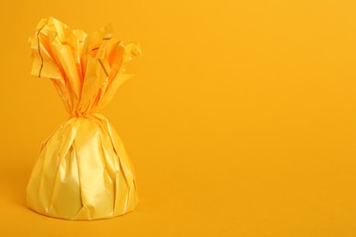 Photo of Candy in bright wrapper on yellow background. Space for text