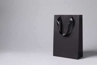 Photo of Black paper bag on light grey background, space for text