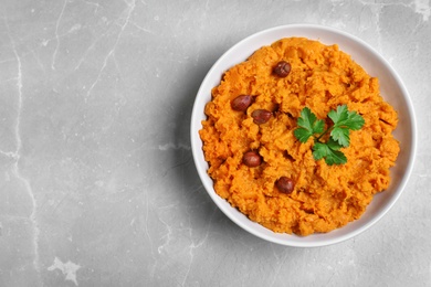 Photo of Bowl of tasty sweet potato puree on grey marble table, top view. Space for text