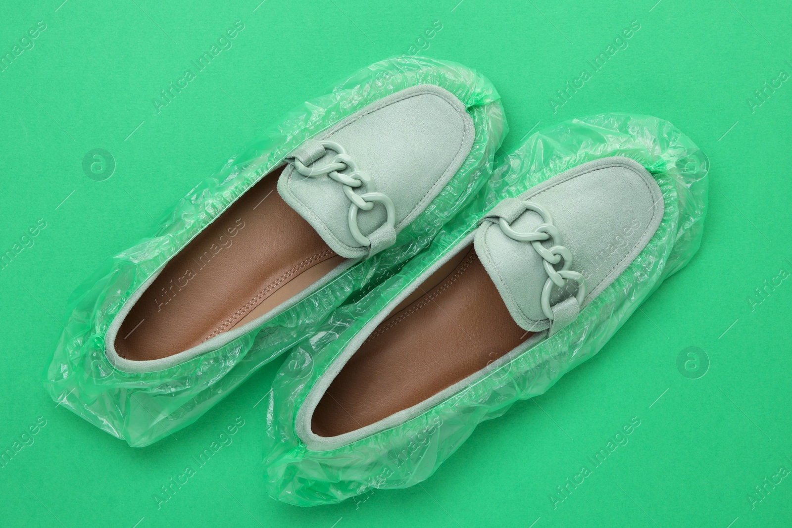 Photo of Women's mules in shoe covers on green background, top view