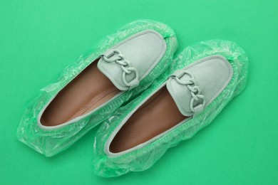 Women's mules in shoe covers on green background, top view