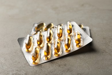 Dietary supplement capsules in blister packs on grey table, closeup