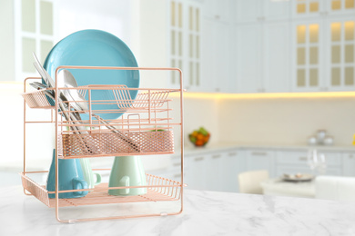 Photo of Clean dishes on drying rack in modern kitchen interior, space for text