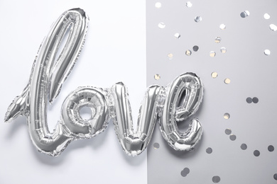 Foil balloon in shape of word LOVE on color background, top view