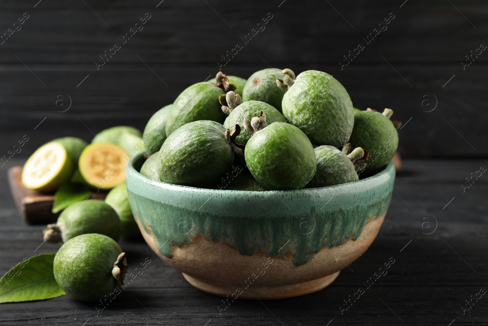 Photo of Fresh green feijoa fruits on black wooden table, closeup