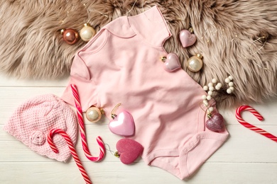 Photo of Flat lay composition with cute baby clothes and decorations on white wooden background. Christmas celebration