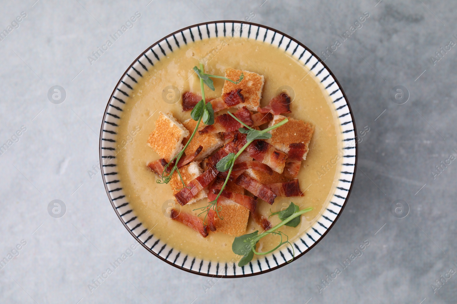 Photo of Delicious lentil soup with bacon and microgreens in bowl on gray table, top view