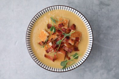 Photo of Delicious lentil soup with bacon and microgreens in bowl on gray table, top view