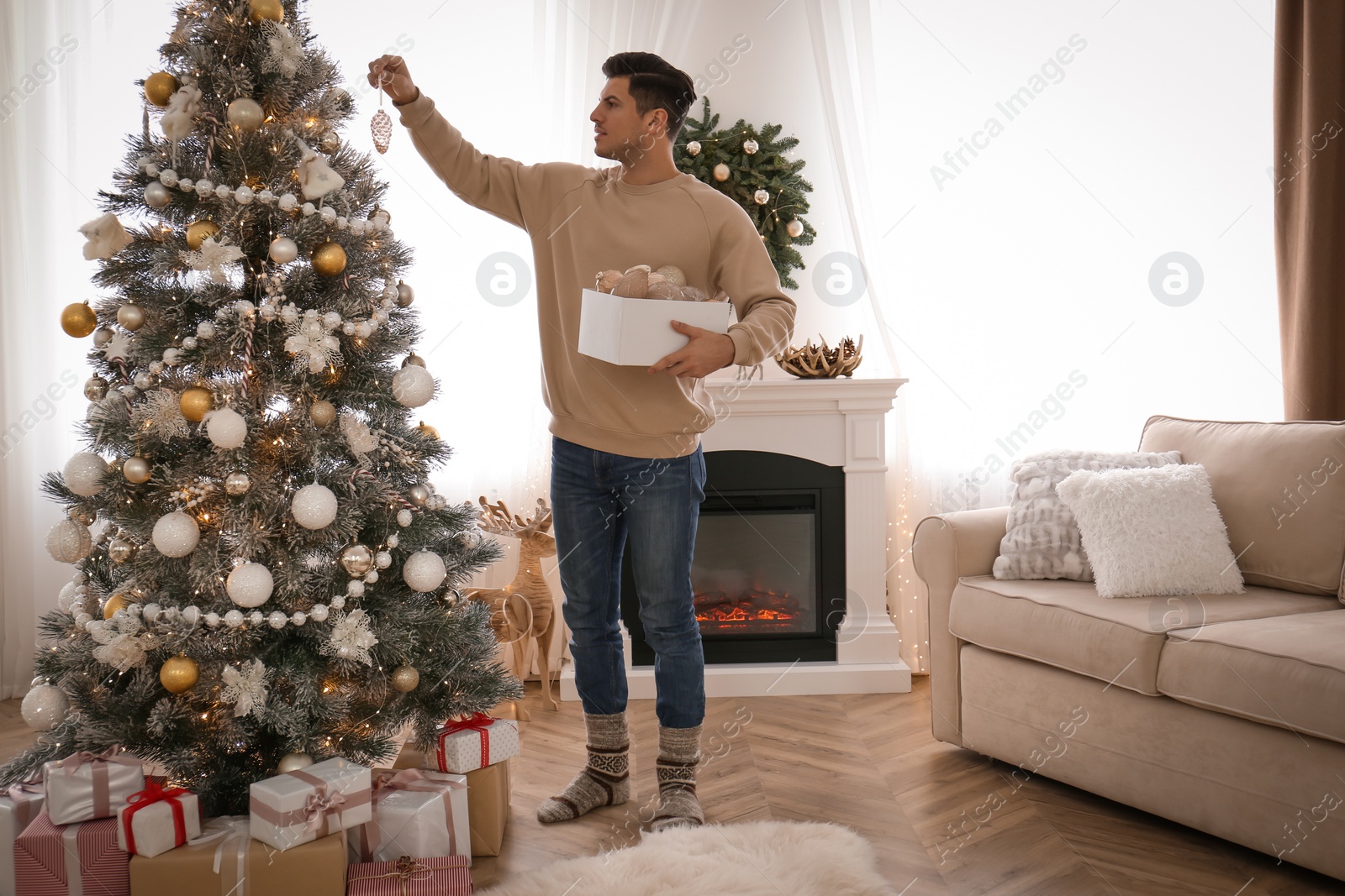 Photo of Man decorating Christmas tree in beautiful room interior