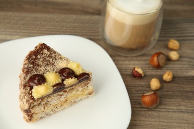 Piece of delicious Kyiv Cake served with coffee on wooden table, closeup