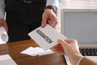 Photo of Employee giving resignation letter to boss in office, closeup