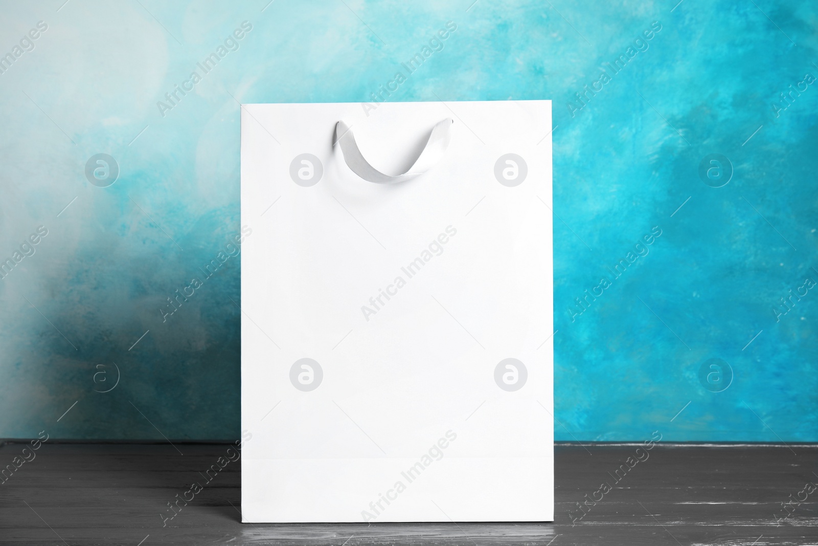 Photo of Paper shopping bag on table against color background. Mock up for design