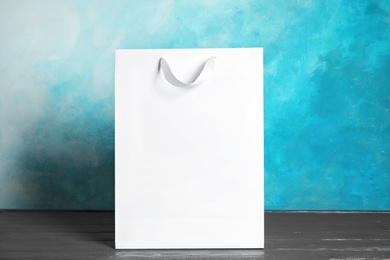 Paper shopping bag on table against color background. Mock up for design