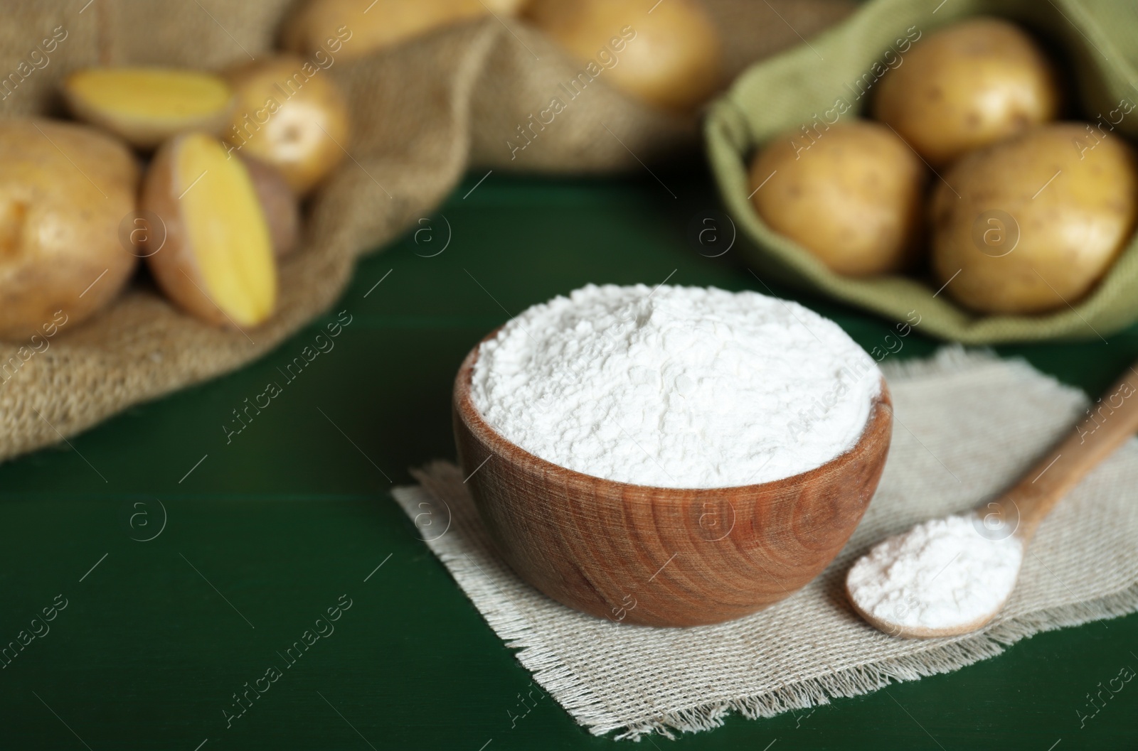 Photo of Starch and fresh raw potatoes on green wooden table. Space for text