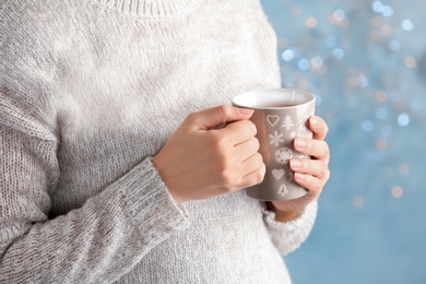 Photo of Young woman with delicious hot cocoa drink on blurred background, closeup