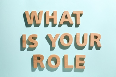 Photo of Phrase What Is Your Role made of wooden letters on light blue background, flat lay