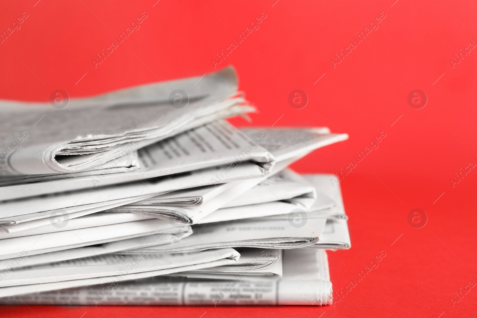Photo of Stack of newspapers on red background, closeup. Journalist's work
