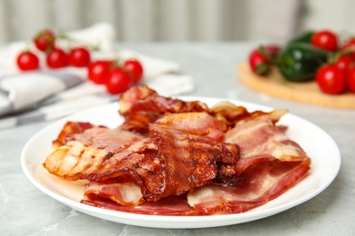 Slices of tasty fried bacon on light marble table indoors