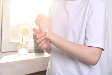 Photo of Woman applying hand cream at home, closeup