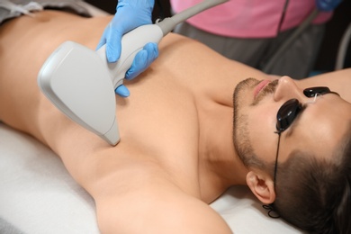 Young man undergoing laser epilation procedure in beauty salon
