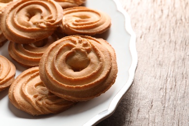 Photo of Plate with Danish butter cookies on wooden table, closeup. Space for text