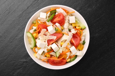 Photo of Tasty salad with Chinese cabbage, carrot, cheese, cucumber, corn and tomato on black table, top view