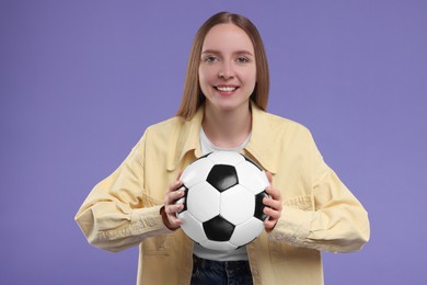 Photo of Happy sports fan with ball on purple background