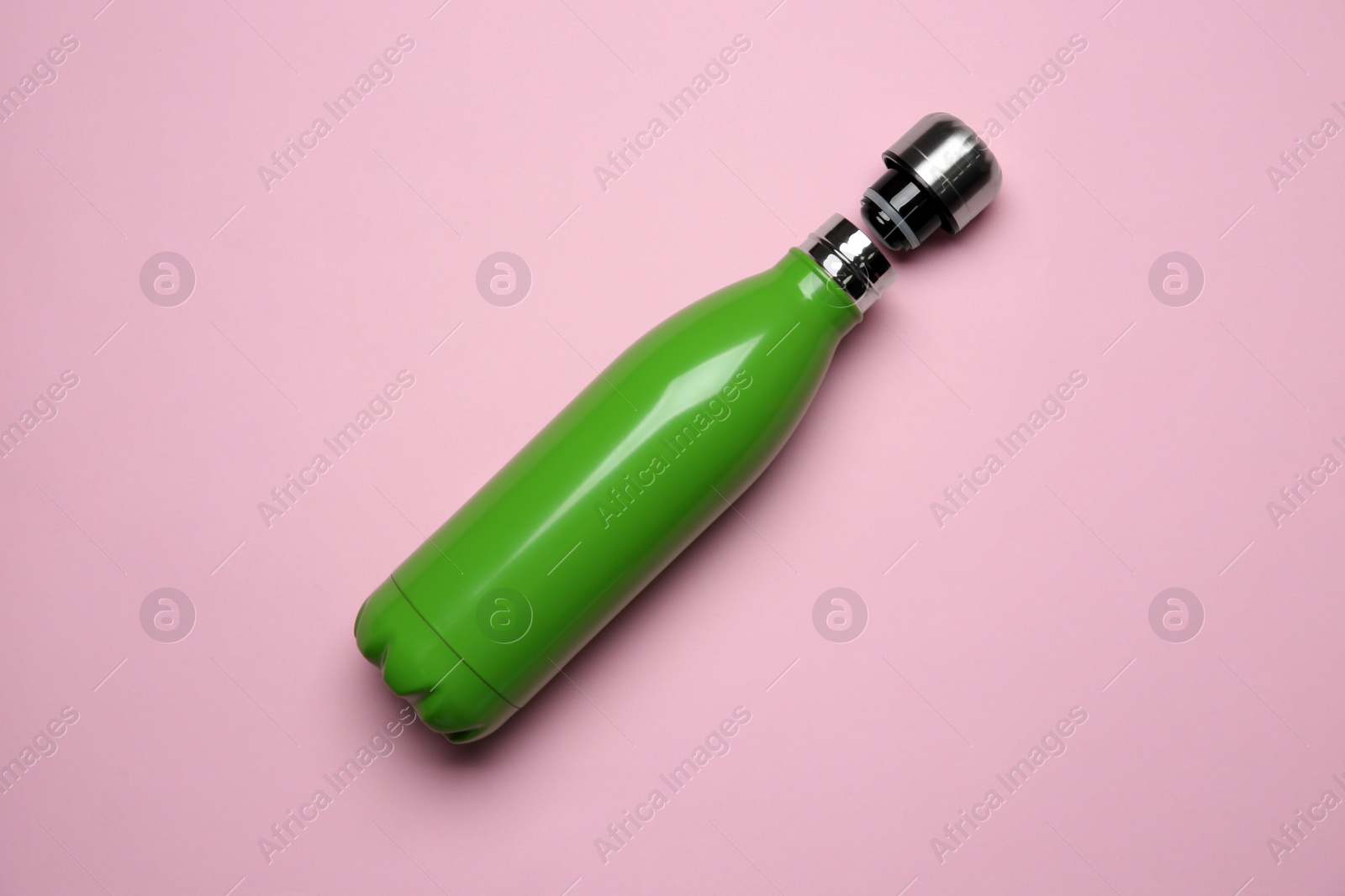 Photo of Green thermo bottle on pink background, top view