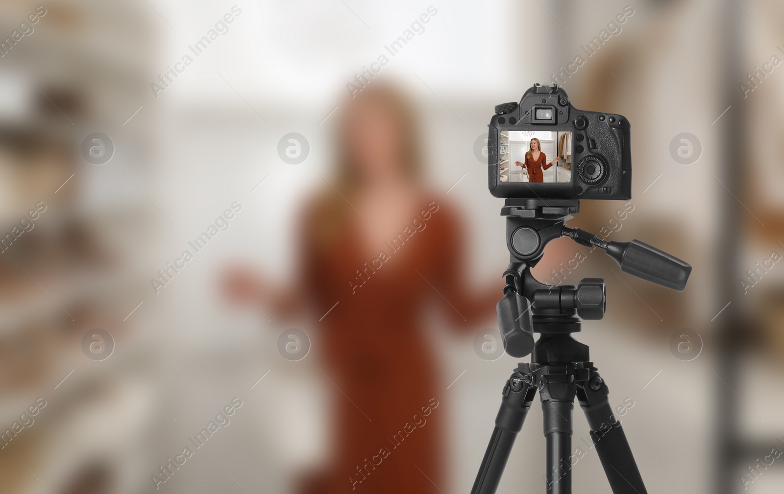 Image of Young woman with stylish purse in dressing room, selective focus on camera display