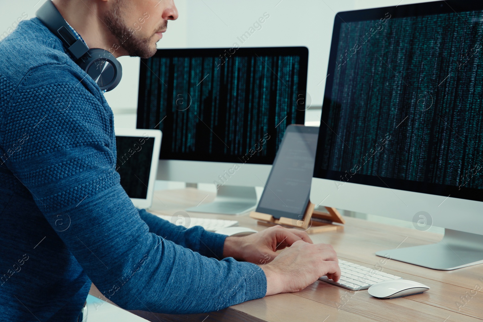 Photo of Programmer with headphones working at desk in office, closeup