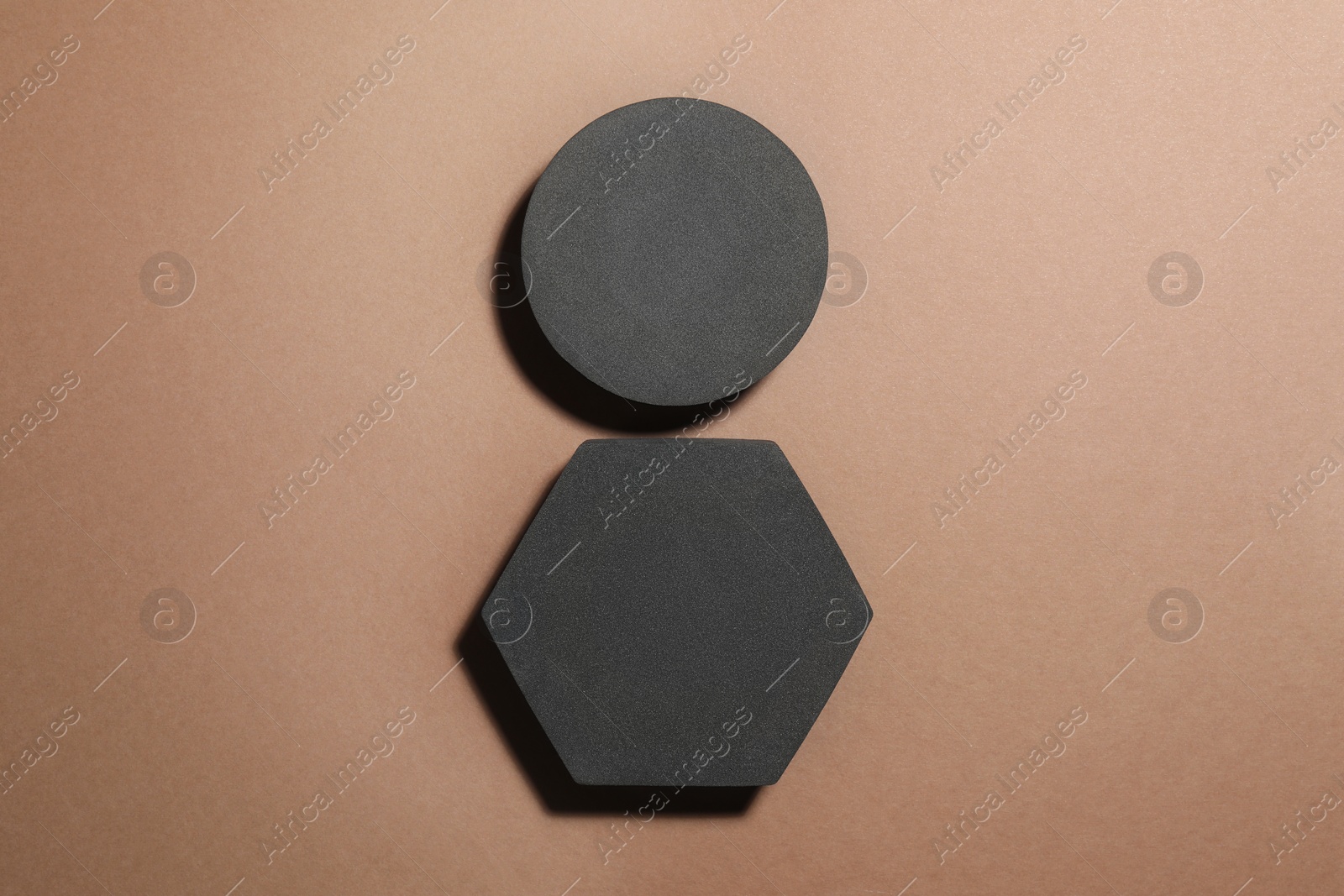 Photo of Black geometric figures on light brown background, flat lay. Stylish presentation for product