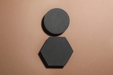 Photo of Black geometric figures on light brown background, flat lay. Stylish presentation for product