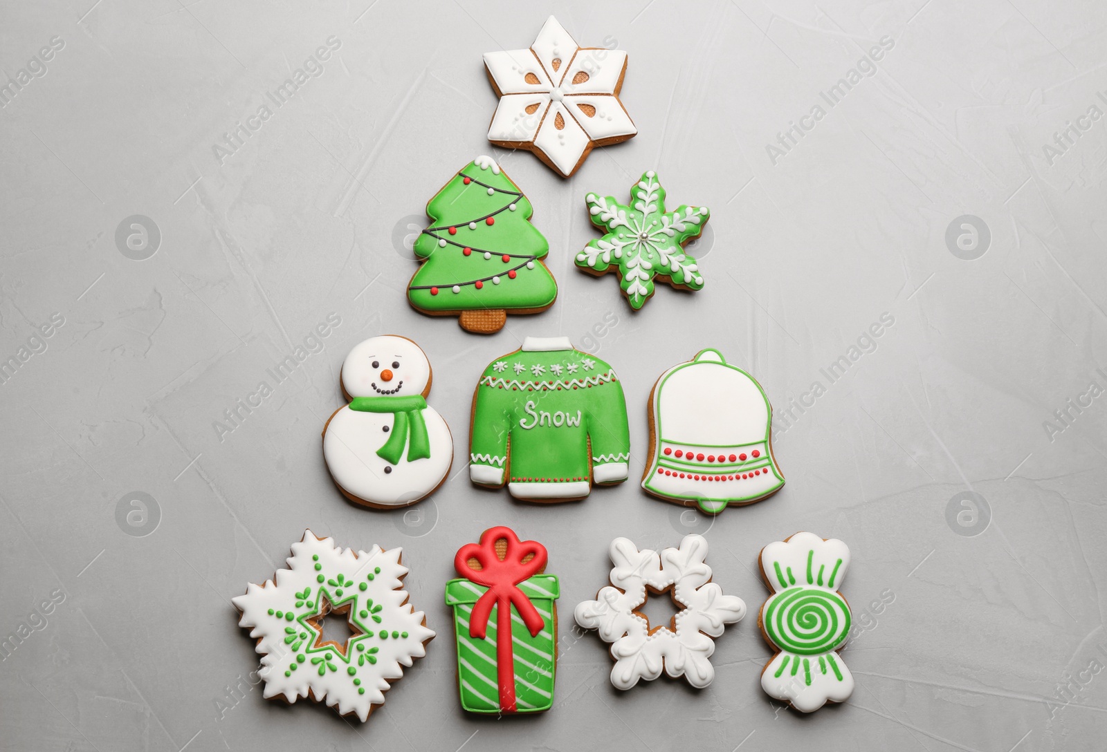 Photo of Christmas tree shape made of delicious decorated gingerbread cookies on light table, flat lay