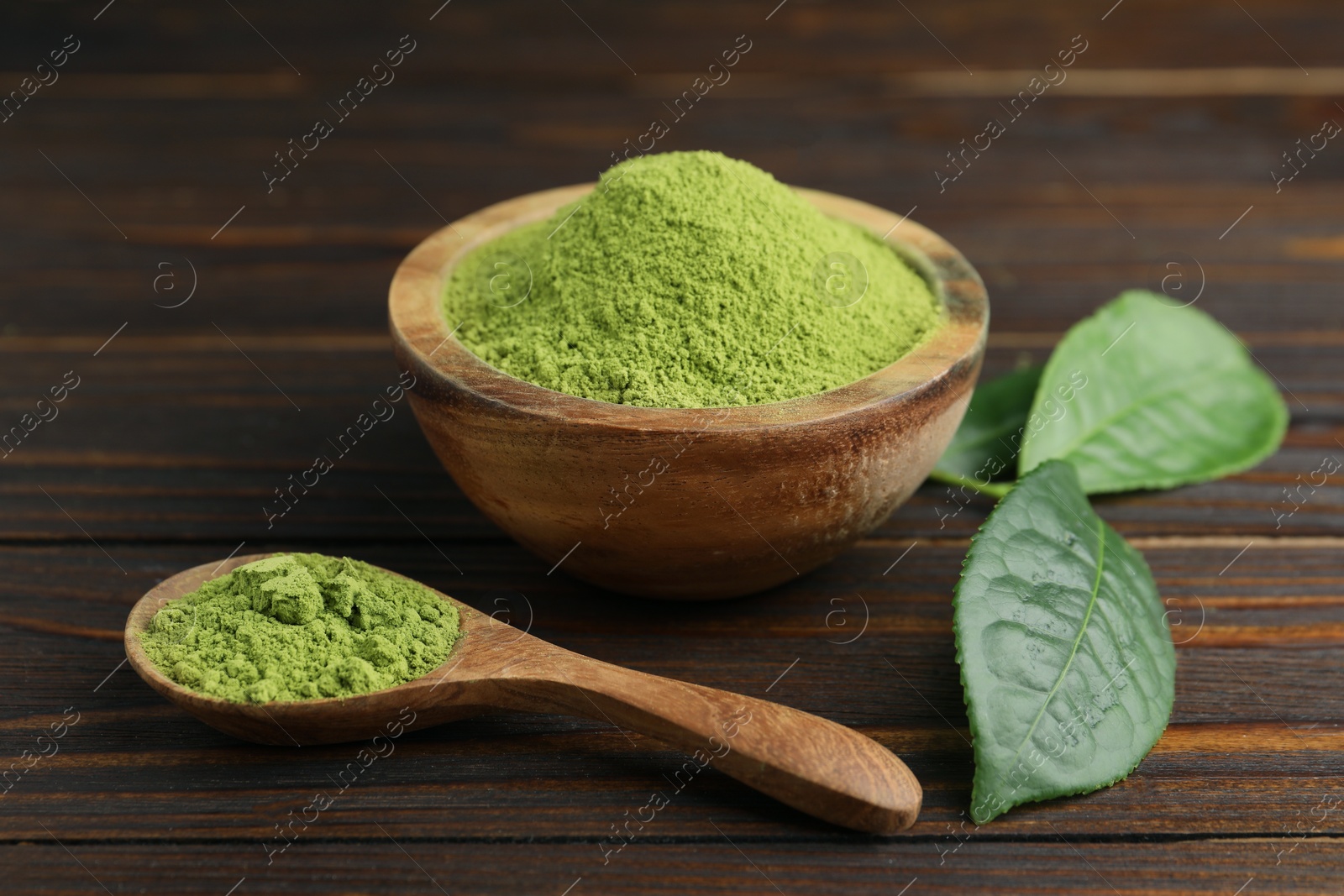 Photo of Bowl and spoon with green matcha powder on wooden table, closeup