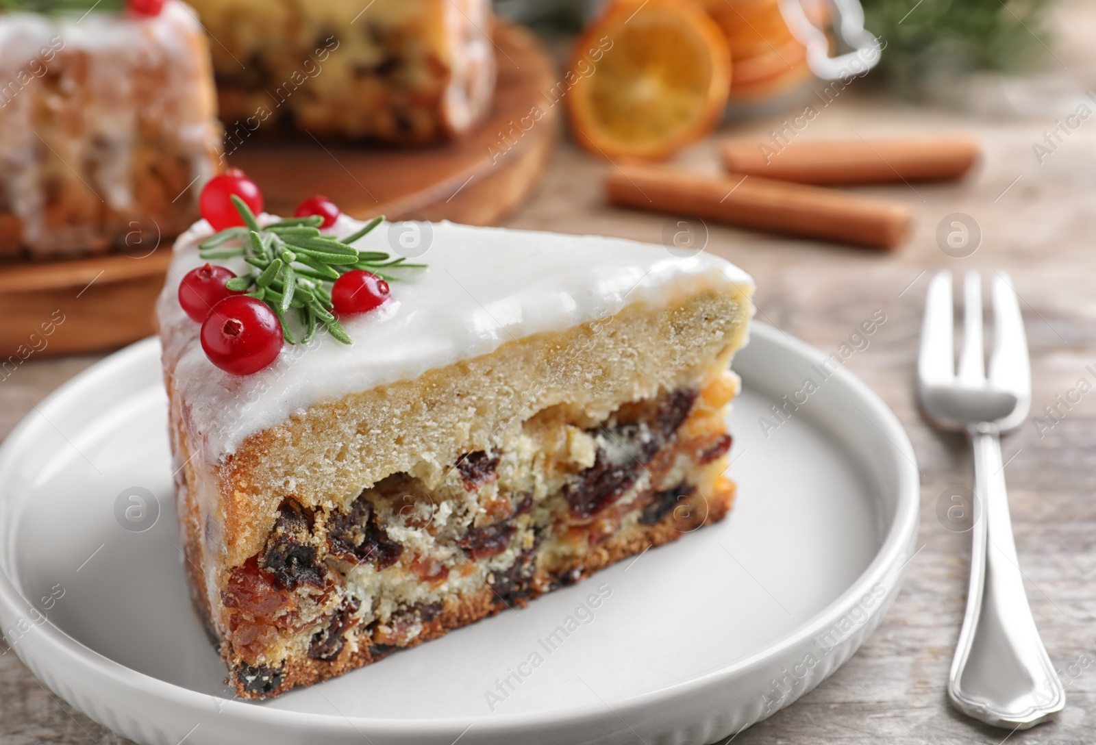 Photo of Slice of traditional Christmas cake decorated with rosemary and cranberries on table, closeup