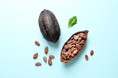 Photo of Cocoa pods and beans on light blue background, flat lay