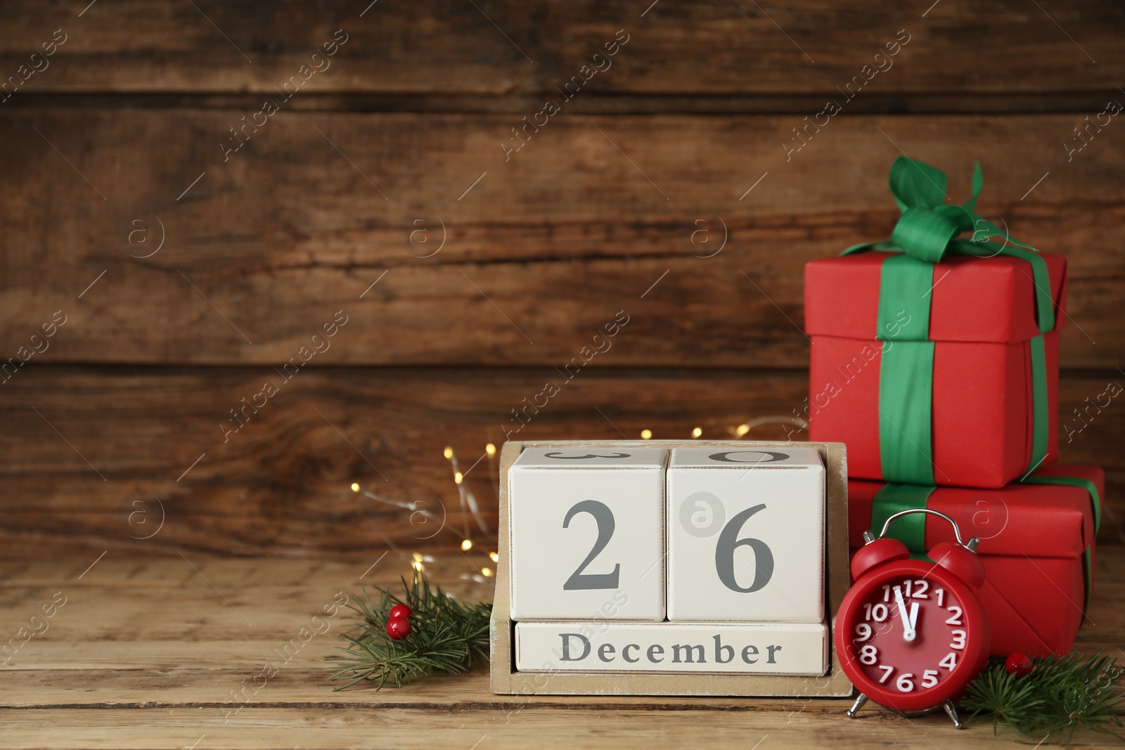 Photo of Block calendar with Boxing Day date, alarm clock and gifts on wooden background, space for text
