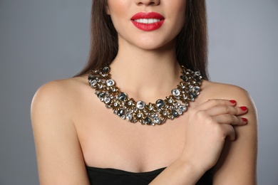 Photo of Beautiful woman with stylish jewelry on grey background, closeup