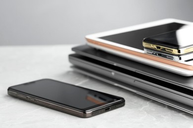 Photo of Stack of electronic devices on grey stone table, closeup