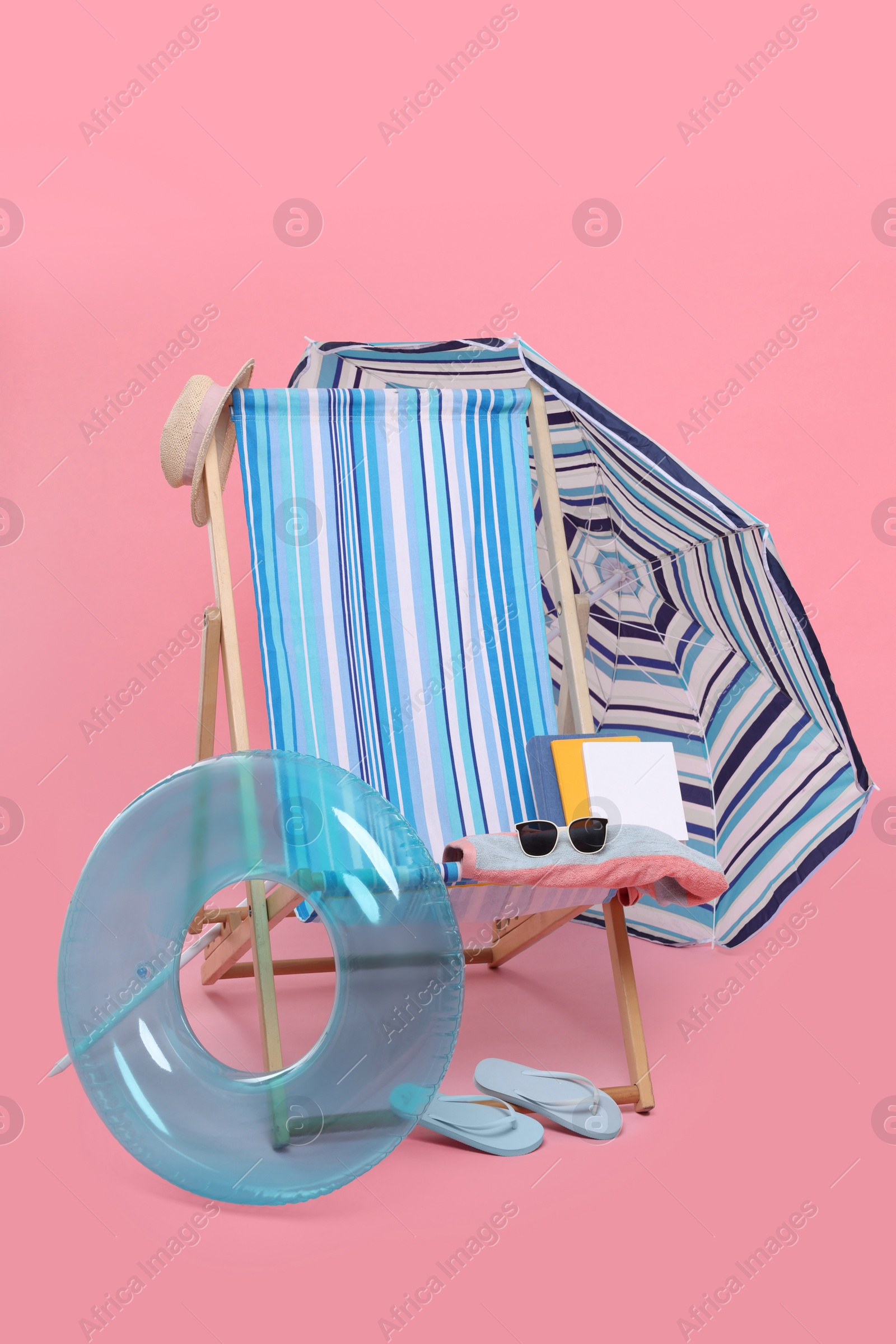 Deck chair, umbrella and other beach accessories on pink background. Summer vacation Photo of Deck chair, umbrella and other beach accessories on pink background. Summer vacation