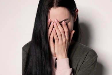 Photo of Upset young woman crying against light background