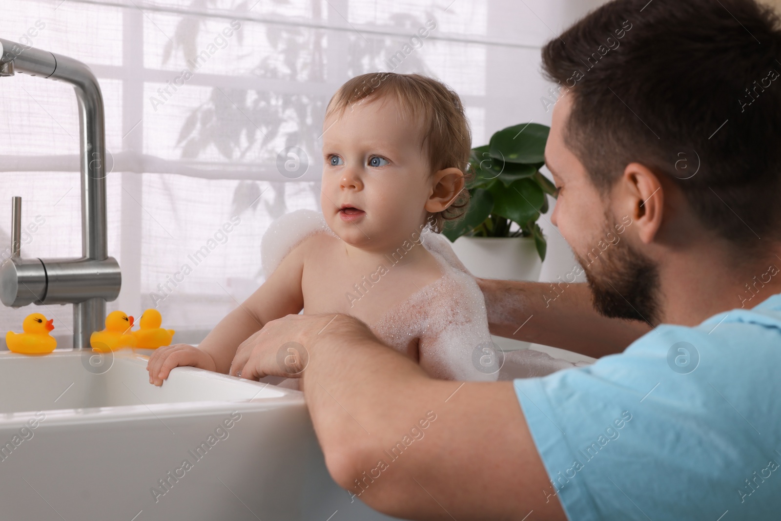 Photo of Father washing his little baby in sink at home