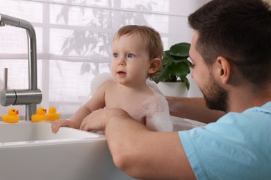 Father washing his little baby in sink at home