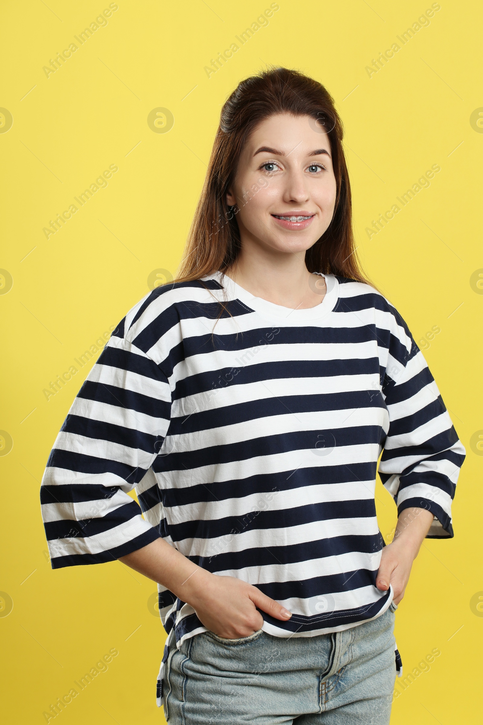 Photo of Portrait of smiling woman with dental braces on yellow background