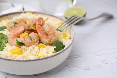 Tasty couscous with shrimps, bell pepper and basil on white textured table, closeup. Space for text